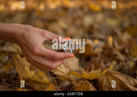 Outdoors photo of traditional hutsul drymba, jaw's harp, silver vargan in female hand on fallen leaves background during autumn day Stock Photo