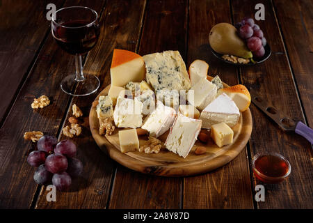 Many sorts of cheese peaces served on wooden board Stock Photo