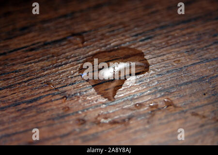Water drop on a floor. Drop on a wooden floor. Stock Photo