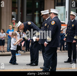 A young parade watcher greets an Austin firefighter with a handshake during Texas' annual Veterans Day parade  honoring military veterans from World War II through recent Iran/Iraq conflicts. Stock Photo