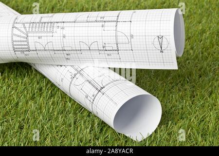 Architectural blueprints on green grass lawn background - house building or buying concept, selective focus Stock Photo