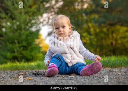 Happy baby rejoices autumn weather and playing in the meadow in the park Stock Photo