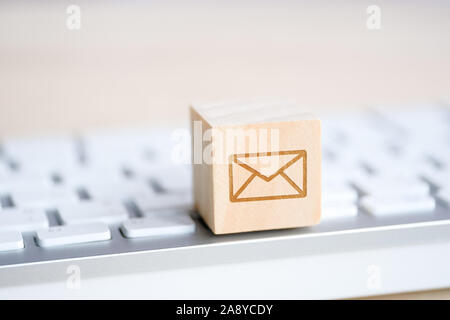 Wooden cube with the image of a mail symbol envelope in his hand. Contact concept for communication. Close up. Stock Photo