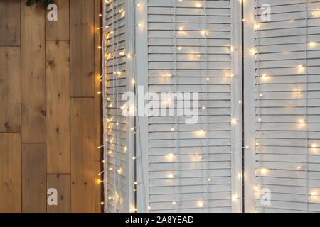 Christmas lights burning on a white wooden background. Xmas background. Stock Photo