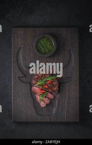 Fillet mignon with chimichurri sauce on wooden cutting board. Stock Photo