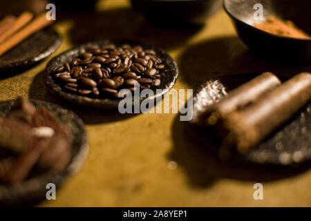 Small dish full of fresh brown coffee beans surrounded by other spices. Stock Photo