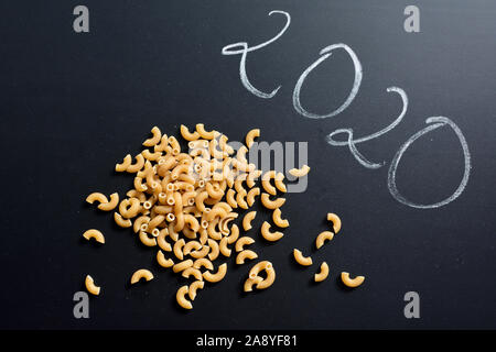 Raw macaroni on black background with number 2020 from above Stock Photo