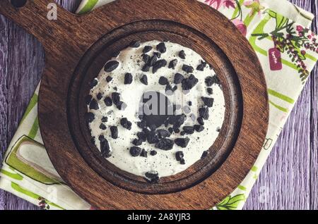 Delicious sweet snack served in a vintage style. Donut with a hole in white topping on violet wood. Stock Photo