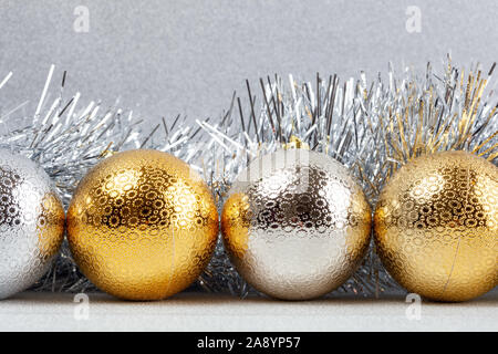 Row of Christmas baubles with silver tinsel on glittery background - closeup Stock Photo