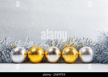 Row of Christmas baubles with silver tinsel on glitter background with copy space Stock Photo