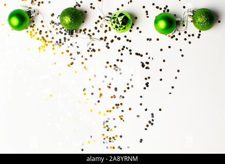Christmas toys of green color and silver and gold confetti on a white background. Flat lay, top view, copy space. Christmas composition. Stock Photo
