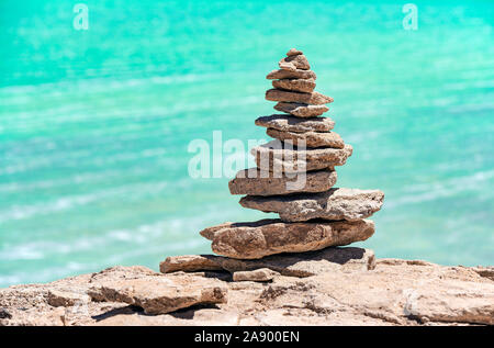 A wish stone pyramid by the Laguna Verde (green lagoon) with its turquoise green waters by the Uyuni salt flat, Bolivia. Stock Photo