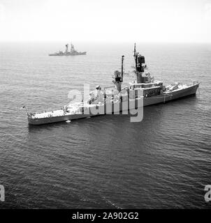 1976 - An aerial starboard quarter view of the guided missile cruiser USS HALSEY (CG 23) anchored off the coast of Southern California.  The guided missile destroyer USS DECATUR (DDG 31) is visible in the background. Stock Photo