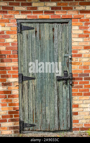 Beautiful, old wood door with old-fashioned hinges on a brick building Stock Photo