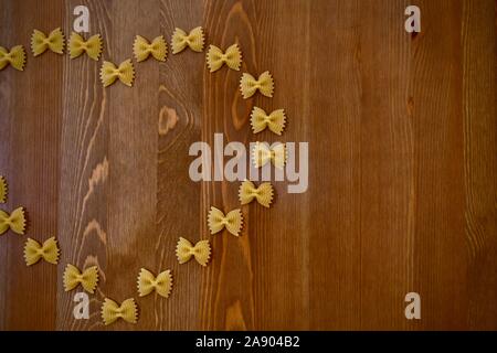 Pasta butterflies or bows, farfalle laid out in the form of a piece of heart on a tree. Stock Photo