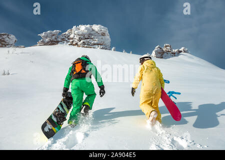 Two snowboarders walking uphill. Backcountry skiing and snowboarding concept at ski resort Stock Photo