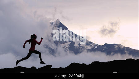 Running woman athlete silhouette trail running in mountain summit background Stock Photo