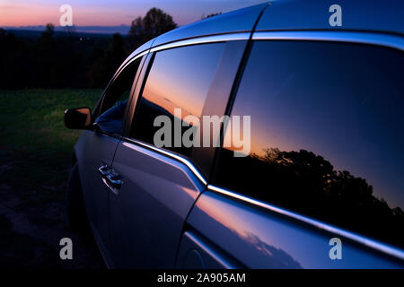 Middletown, CT USA. Nov 2019. Driver inside van enjoying a New England fall sunset as reflected on the cars window. Stock Photo