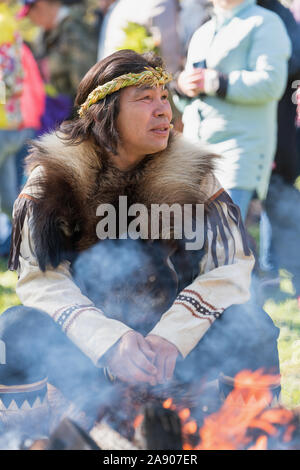 Itelmen shaman in traditional clothing aboriginal Kamchatka Peninsula sits near bonfire during Itelmens national ritual festival of thanksgiving natur Stock Photo
