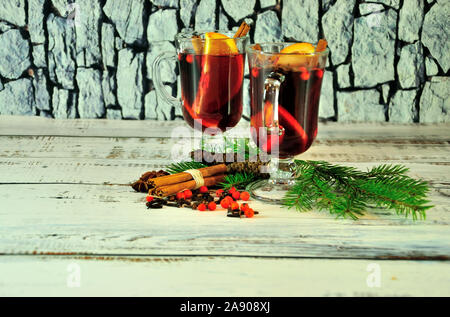 Christmas composition, two glasses with mulled wine, with fruit slices and spices, decorated with fir cones and branches. Close-up. Stock Photo