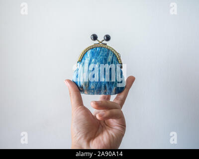 Hand holding small vintage coin purse made by indigo blue fabric isolated on white background. Stock Photo