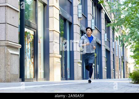 Young Japanese man running downtown Tokyo Stock Photo