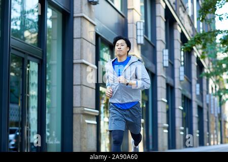 Young Japanese man running downtown Tokyo Stock Photo