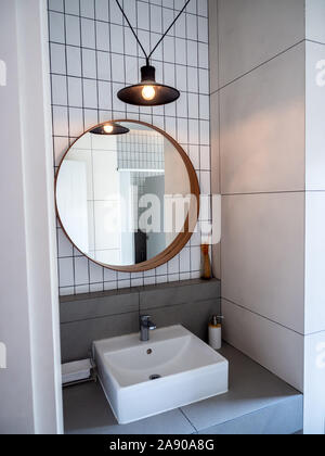 SEPTEMBER 28, 2019 : Bangkok, Thailand : Round mirror on black and white grid wall, black hanging lamp, sink bath, faucet and aroma sticks, modern dec Stock Photo