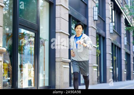 Young Japanese man running downtown Tokyo Stock Photo