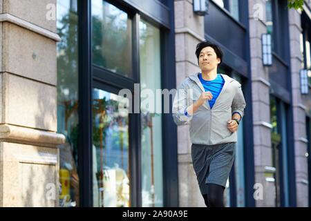 Young Japanese man running downtown Tokyo Stock Photo