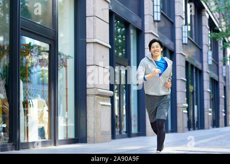 Young Japanese man running downtown Tokyo Stock Photo