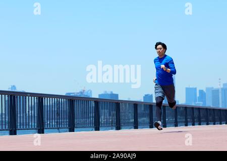 Young Japanese man running downtown Tokyo Stock Photo