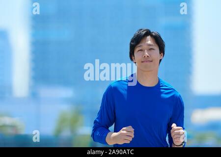 Young Japanese man running downtown Tokyo Stock Photo