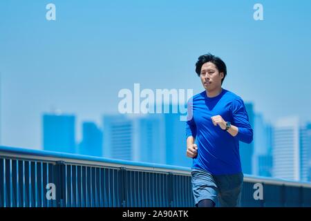 Young Japanese man running downtown Tokyo Stock Photo