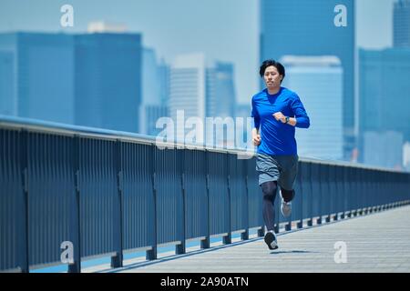 Young Japanese man running downtown Tokyo Stock Photo