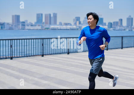 Young Japanese man running downtown Tokyo Stock Photo