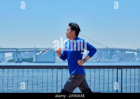 Young Japanese man running downtown Tokyo Stock Photo