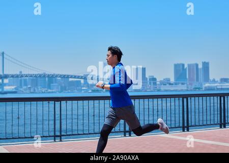 Young Japanese man running downtown Tokyo Stock Photo