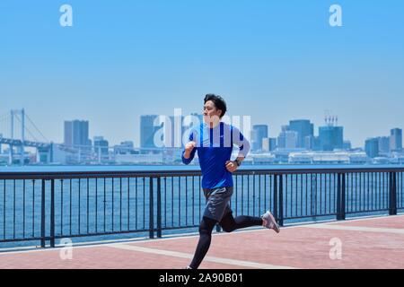 Young Japanese man running downtown Tokyo Stock Photo