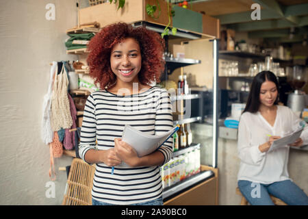 Beautiful woman owning coffee shop with friend feeling happy Stock Photo