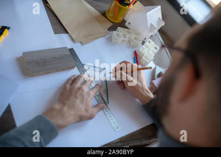 Close up of man using ruler and pencil while making sketches Stock Photo