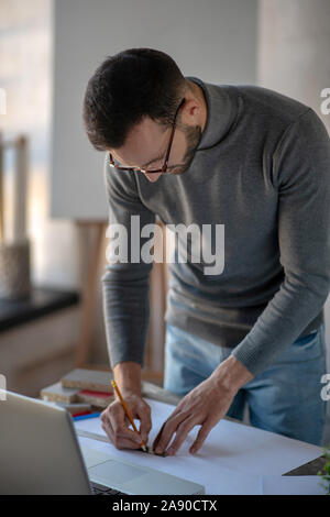 Interior designer wearing glasses feeling busy making sketches Stock Photo