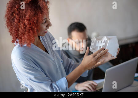 Designer holding house model while standing near colleague Stock Photo