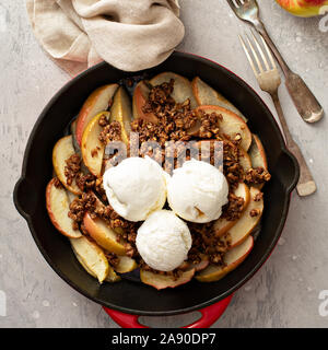 Apple crumble with pecans in a cast iron pan topped with ice cream Stock Photo