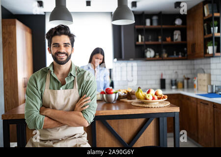 Happy young friends loving couple chefs on the kitchen cooking. Stock Photo