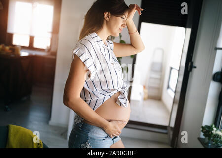 Pains of pregnancy. Depressed pregnant woman holding hand on head Stock Photo