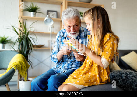 Grandparent enjoy spending time laughing with little girl grandchild at home Stock Photo
