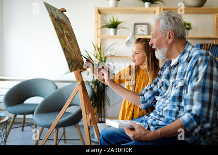 Portrait of senior man, grandfather teaching children painting. Happy family time Stock Photo