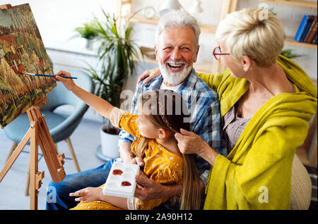Happy grandparents and granddaughter drawing, painting together Stock Photo