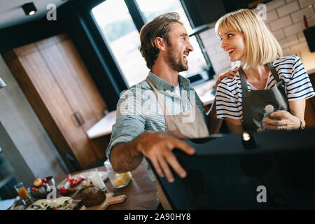 Happy couple cooking together. Husband and wife in their kitchen at home preparing healthy food Stock Photo
